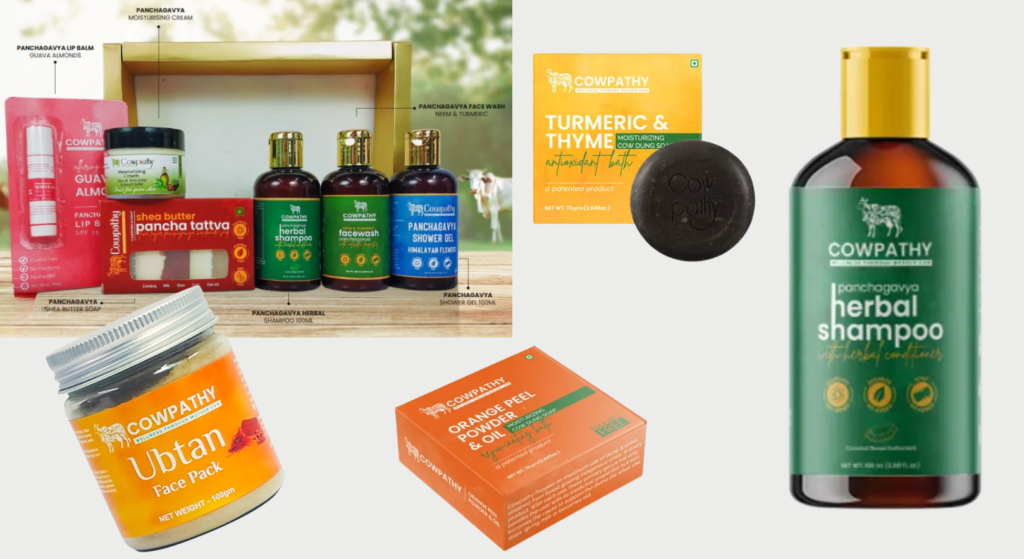 A collection of Cowpathy Ayurveda skincare and haircare products, including face packs, soaps, shampoos, lip balm, and creams, all displayed in their respective colorful packaging on a light background.